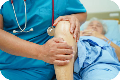 A doctor examines the knee of an elderly surgical patient who is lying on a hospital bed