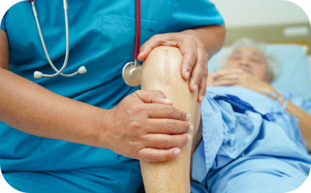 A doctor examines the knee of an elderly surgical patient who is lying on a hospital bed