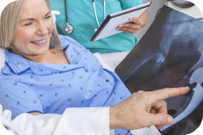 A doctor shows an elderly surgical patient an x-ray of her hip with the hip replacement prosthetic