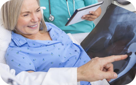 A doctor shows an elderly surgical patient an x-ray of her hip with the hip replacement prosthetic